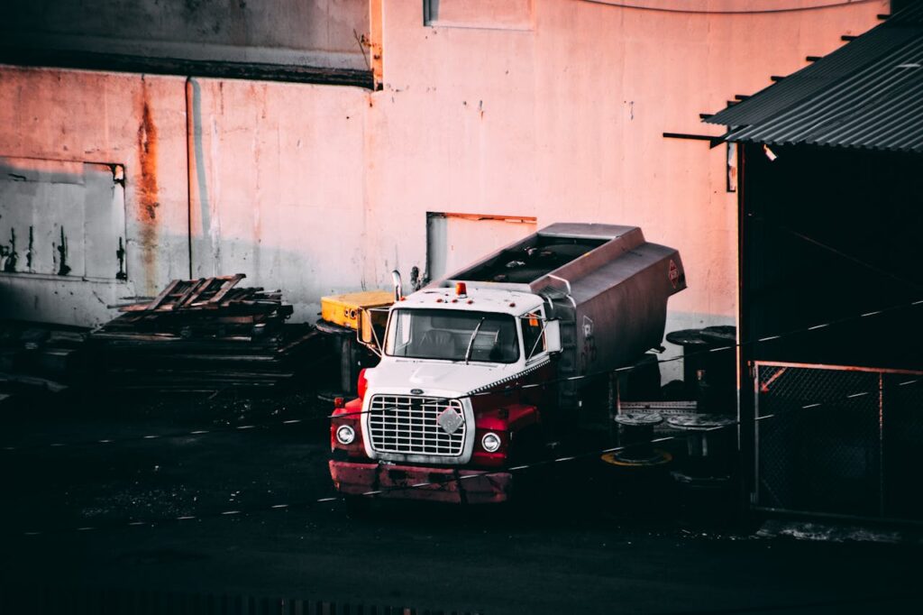 A vintage industrial truck parked at a junkyard during sunset, casting warm hues.